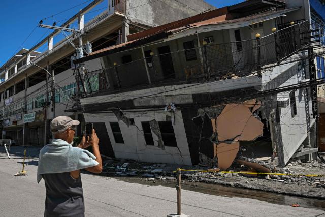 A man takes a photo of a collapsed building after a 7.8 magnitude earthquake in General Santos City on June 9, 2026. A 7.8-magnitude earthquake in the southern Philippines on June 8 killed at least 35 people, according to provincial authorities, after toppling buildings and sparking tsunami warnings across the region. (Photo by Jam STA ROSA / AFP)