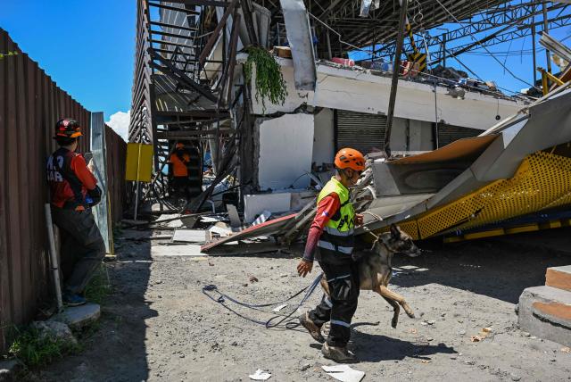 Responders and a rescue dog conduct a search and rescue operations outside a collapsed building after a 7.8 magnitude earthquake in General Santos City on June 9, 2026. A 7.8-magnitude earthquake in the southern Philippines on June 8 killed at least 35 people, according to provincial authorities, after toppling buildings and sparking tsunami warnings across the region. (Photo by Jam STA ROSA / AFP)