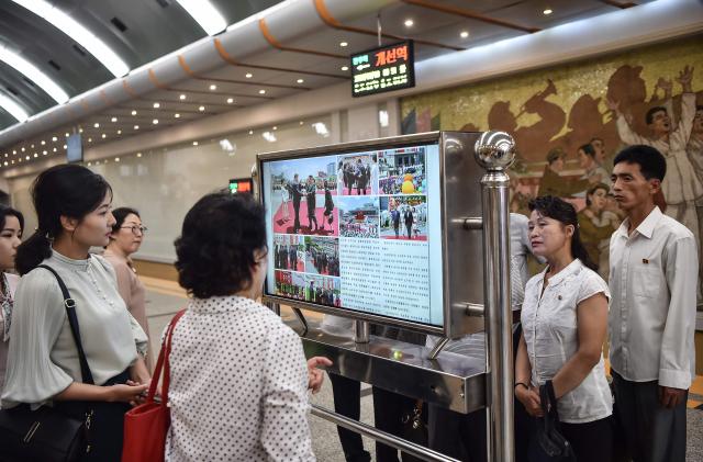 People look at a screen with the newspaper "Rodongsinmun" showing the news on the visit of China's President Xi Jinping, in the Kaeson Station of the Pyongyang Metro in Pyongyang on June 9, 2026. China's President Xi Jinping made a rare visit to North Korea on June 8, where he proclaimed a willingness to bring ties to "new heights" during a meeting with Kim Jong Un. (Photo by KIM Won Jin / AFP)