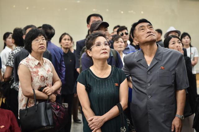 People watch a news program on the visit of China's President Xi Jinping, in the Kaeson Station of the Pyongyang Metro in Pyongyang on June 9, 2026. China's President Xi Jinping made a rare visit to North Korea on June 8, where he proclaimed a willingness to bring ties to "new heights" during a meeting with Kim Jong Un. (Photo by KIM Won Jin / AFP)