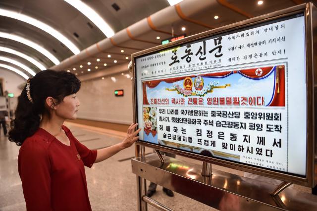 A woman looks at a screen with the newspaper "Rodongsinmun" showing the news on the visit of China's President Xi Jinping, in the Kaeson Station of the Pyongyang Metro in Pyongyang on June 9, 2026. China's President Xi Jinping made a rare visit to North Korea on June 8, where he proclaimed a willingness to bring ties to "new heights" during a meeting with Kim Jong Un. (Photo by KIM Won Jin / AFP)