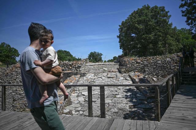 A visitor and a baby walk in the ruins of the ancient city of Troy in Çanakkale on June 2, 2026. A gift from the film set of "Troy", the giant Trojan Horse replica looms over the port of Canakkale on the Dardanelles Strait in western Turkey. First related by Homer, then retold for the silver screen in 2004, with Brad Pitt as Achilles, the legend of the ancient city travels to Rome's Colosseum this week, where a major new exhibition opens on June 12, 2026. (Photo by Ozan KOSE / AFP)