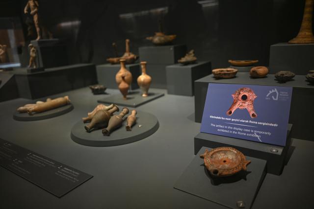 This photograph shows a sign which reads as “This artefact is temporarily on display at the Rome exhibition” at the Troy Museum in Canakkale on June 2, 2026. A gift from the film set of "Troy", the giant Trojan Horse replica looms over the port of Canakkale on the Dardanelles Strait in western Turkey. First related by Homer, then retold for the silver screen in 2004, with Brad Pitt as Achilles, the legend of the ancient city travels to Rome's Colosseum this week, where a major new exhibition opens on June 12, 2026. (Photo by Ozan KOSE / AFP)