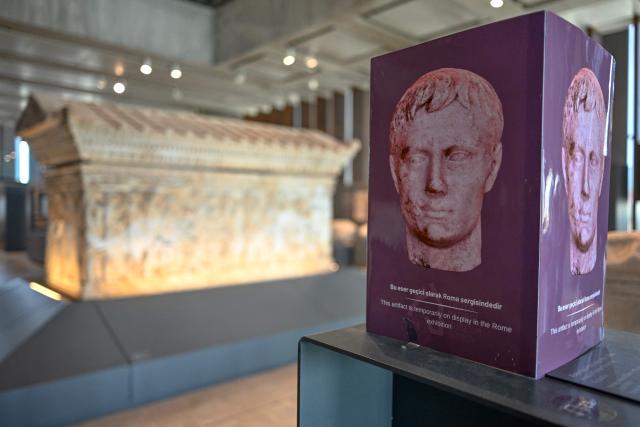 This photograph shows a sign which reads as “This artefact is temporarily on display at the Rome exhibition” at the Troy Museum in Canakkale on June 2, 2026. A gift from the film set of "Troy", the giant Trojan Horse replica looms over the port of Canakkale on the Dardanelles Strait in western Turkey. First related by Homer, then retold for the silver screen in 2004, with Brad Pitt as Achilles, the legend of the ancient city travels to Rome's Colosseum this week, where a major new exhibition opens on June 12, 2026. (Photo by Ozan KOSE / AFP)