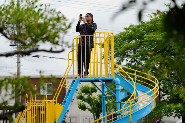 A man records with his phone from the top of a playground slide as hunters and zoo staff search for a wild bear in Utsunomiya, north of Tokyo, on June 9, 2026. A bear roaming the streets of a Japanese city for days forced the closure of nearly 100 schools, as dozens of hunters and officials searched for the animal. (Photo by Yuichi YAMAZAKI / AFP)