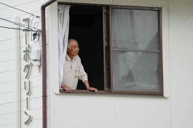 A resident looks out from a home as hunters and zoo staff search for a wild bear in Utsunomiya, north of Tokyo, on June 9, 2026. A bear roaming the streets of a Japanese city for days forced the closure of nearly 100 schools, as dozens of hunters and officials searched for the animal. (Photo by Yuichi YAMAZAKI / AFP)