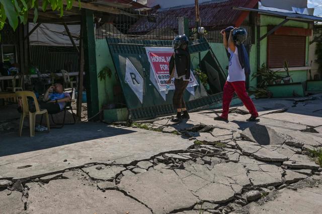 People walk along a damaged road after a 7.8 magnitude earthquake in General Santos City on June 9, 2026. A 7.8-magnitude earthquake in the southern Philippines on June 8 killed at least 35 people, according to provincial authorities, after toppling buildings and sparking tsunami warnings across the region. (Photo by Jam STA ROSA / AFP)