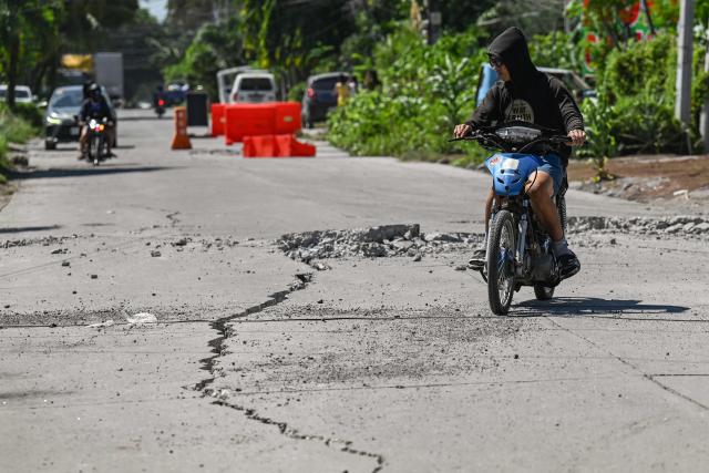 A man rides along a damaged road after a 7.8 magnitude earthquake in General Santos City on June 9, 2026. A 7.8-magnitude earthquake in the southern Philippines on June 8 killed at least 35 people, according to provincial authorities, after toppling buildings and sparking tsunami warnings across the region. (Photo by Jam STA ROSA / AFP)
