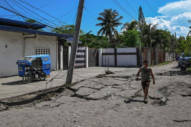 A man walks along a damaged road after a 7.8 magnitude earthquake in General Santos City on June 9, 2026. A 7.8-magnitude earthquake in the southern Philippines on June 8 killed at least 35 people, according to provincial authorities, after toppling buildings and sparking tsunami warnings across the region. (Photo by Jam STA ROSA / AFP)