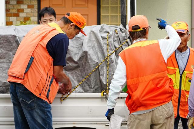 Hunters stand next to a truck carrying a sedated wild bear after it was captured in Utsunomiya, north of Tokyo, on June 9, 2026. A bear roaming the streets of a Japanese city for days forced the closure of nearly 100 schools, as dozens of hunters and officials searched for the animal. (Photo by Yuichi YAMAZAKI / AFP)