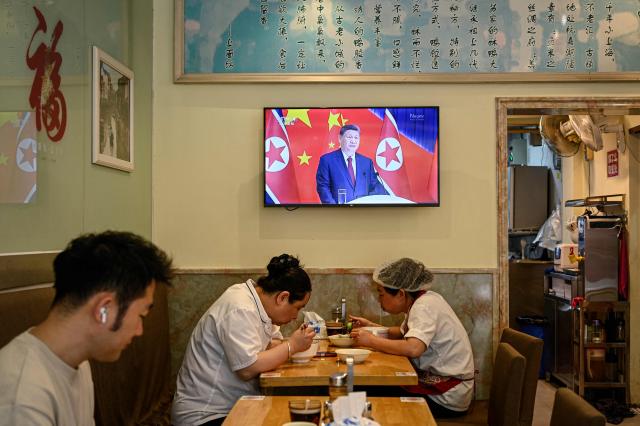 People eat at a restaurant in Shanghai next to a screen showing a news program about the meeting between Chinese President Xi Jinping and North Korean leader Kim Jong Un in Pyongyang, on June 9, 2026. China's President Xi Jinping made a rare visit to North Korea on June 8, where he proclaimed a willingness to bring ties to "new heights" during a meeting with Kim Jong Un. (Photo by Jade GAO / AFP)