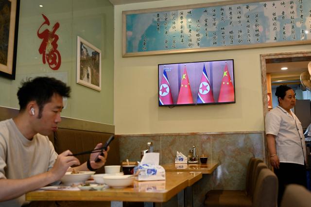 A man eats at a restaurant in Shanghai next to a screen showing a news program about the meeting between Chinese President Xi Jinping and North Korean leader Kim Jong Un in Pyongyang, on June 9, 2026. China's President Xi Jinping made a rare visit to North Korea on June 8, where he proclaimed a willingness to bring ties to "new heights" during a meeting with Kim Jong Un. (Photo by Jade GAO / AFP)