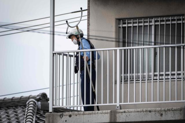A police officer holding animal capture equipment looks for a wild bear during a widescale search for the animal in Utsunomiya, north of Tokyo, on June 9, 2026. A bear roaming the streets of a Japanese city for days forced the closure of nearly 100 schools, as dozens of hunters and officials searched for the animal. (Photo by Yuichi YAMAZAKI / AFP)