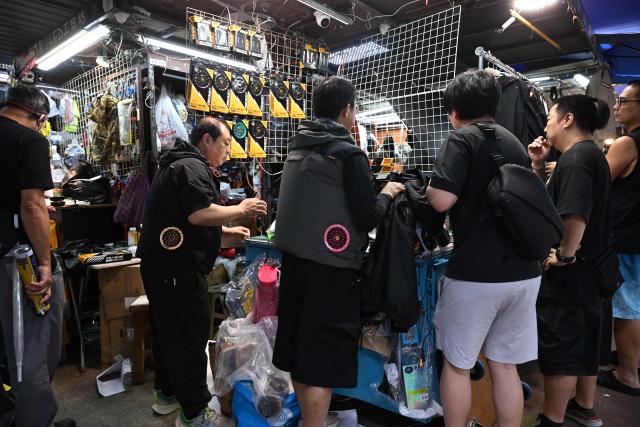People shop for jackets with built in fans at a store in Hong Kong on June 9, 2026 as the city enters the hot summer months. (Photo by Peter PARKS / AFP)