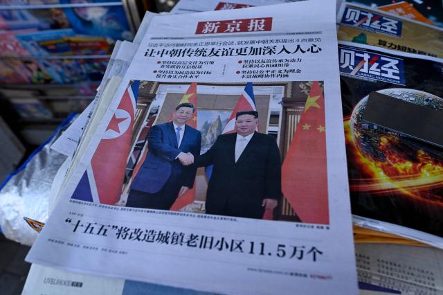 A newspaper front page photo shows Chinese President Xi Jinping (L) shaking hands with North Korean leader Kim Jong Un in Pyongyang, as seen at a news stand in Beijing on June 9, 2026. (Photo by WANG Zhao / AFP)