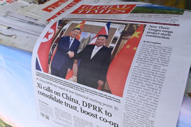 A newspaper front page photo shows Chinese President Xi Jinping (L) shaking hands with North Korean leader Kim Jong Un in Pyongyang, as seen at a news stand in Beijing on June 9, 2026. (Photo by WANG Zhao / AFP)