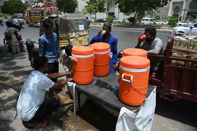 Commuters drink cold water served along a street during a hot summer day in Karachi on June 9, 2026. (Photo by Rizwan TABASSUM / AFP)