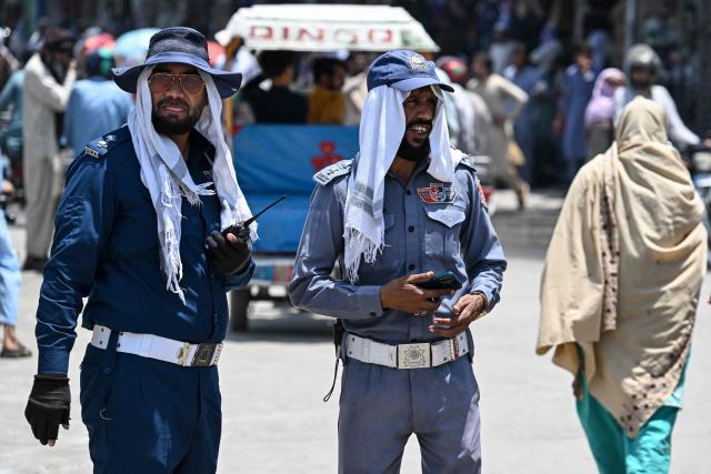 Traffic police personnel cover their heads with cloth as they stand at a road junction amid a heatwave in Rawalpindi on June 9, 2026.  (Photo by Aamir QURESHI / AFP)