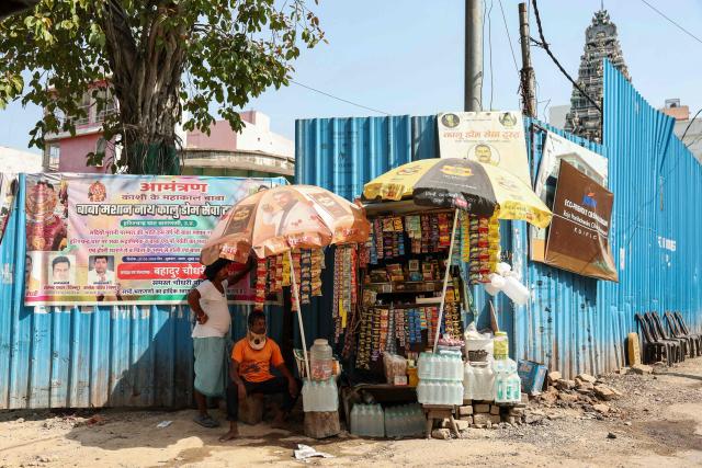People take shelter under an umbrella at a roadside stall on a hot summer day in Varanasi on June 9, 2026. (Photo by Niharika KULKARNI / AFP)