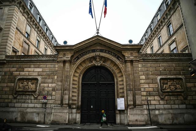(FILES) This photograph taken on December 6, 2022, shows a pedestrian walking past the main entrance of the Banque de France building in Paris. The Banque de France will lower its 2026 growth forecasts, confirmed new governor Emmanuel Moulin on June 9, 2026. (Photo by Christophe ARCHAMBAULT / AFP)