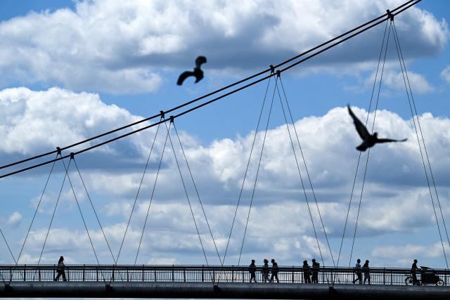 People cross the Holbeinsteg pedestrian bridge over the river Main on a cloudy day in Frankfurt am Main, western Germany, on June 9, 2026 with air temperature reaching 19 degrees Celsius. (Photo by Kirill KUDRYAVTSEV / AFP)