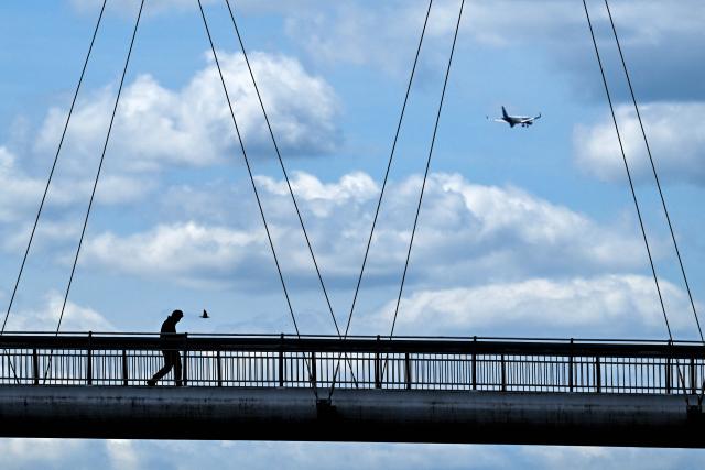 A person crosses the Holbeinsteg pedestrian bridge over the river Main on a cloudy day in Frankfurt am Main, western Germany, on June 9, 2026 with air temperature reaching 19 degrees Celsius. (Photo by Kirill KUDRYAVTSEV / AFP)