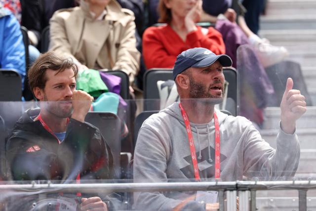 Tennis coach Andrew Robertson (R), along with Alexis Canter, cheer on Britain's Emma Raducanu as she plays against Russia's Anna Blinkova during their round of 32, singles match at the HSBC WTA tennis Championships at Queen's Club in west London on June 9, 2026. (Photo by Adrian Dennis / AFP)