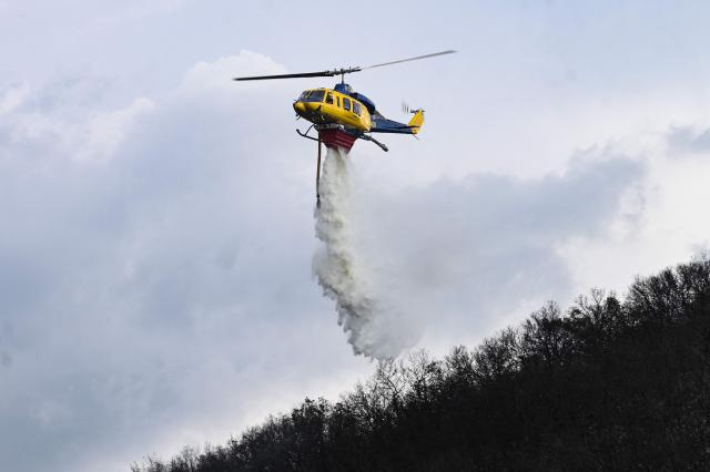 A McDermott Aviation Bell 214ST SuperTransport helicopter drops water over a forest fire in Thessaloniki on June 9, 2026. (Photo by Sakis Mitrolidis / AFP)