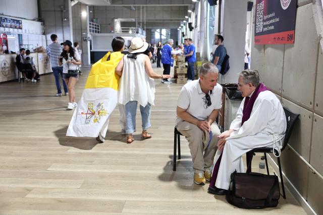 A faithful confess to a priest prior a prayer vigil at the Lluis Companys Olympic Stadium in Barcelona, on June 9, 2026. Pope Leo XIV is visiting Spain June 6-12 with stops in Madrid, Barcelona, and the Canary Islands, where he will meet with migrants and organisations dedicated to helping them. (Photo by Josep LAGO / AFP)