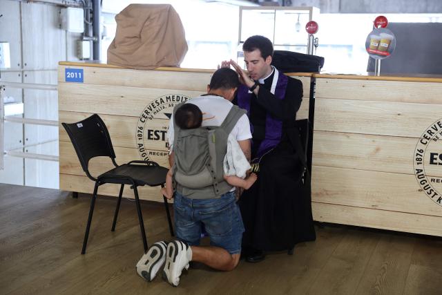 A priest blesses a faithful prior a prayer vigil at the Lluis Companys Olympic Stadium in Barcelona, on June 9, 2026. Pope Leo XIV is visiting Spain June 6-12 with stops in Madrid, Barcelona, and the Canary Islands, where he will meet with migrants and organisations dedicated to helping them. (Photo by Josep LAGO / AFP)
