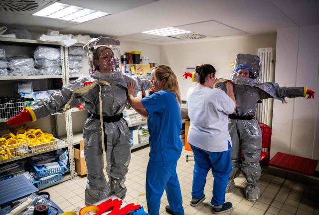 Nurses help their colleagues get into their PPE (Personal Protection Equipment) as they simulate the reception of a patient with a highly infectious disease such as Ebola, at the special isolation ward of the Department of Infectious Diseases at the Charite Virchow hospital in Berlin on June 9, 2026. The German hospital discharged a US man who caught Ebola in the Democratic Republic of Congo, after 17 days of antiviral treatment and medical care cured him of the often deadly infection. The Charite public hospital in Berlin said the man -- who had been working as a surgeon for a Christian missionary group in the DRC -- and his five family members who had all been in quarantine were in "good health" and permitted to leave. (Photo by John MACDOUGALL / AFP)