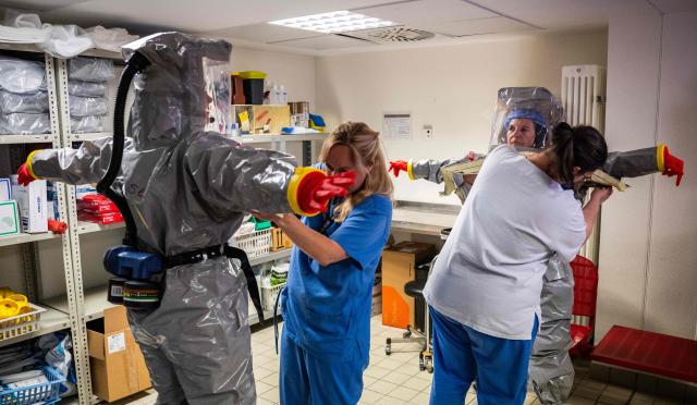 Nurses help their colleagues get into their PPE (Personal Protection Equipment) as they simulate the reception of a patient with a highly infectious disease such as Ebola, at the special isolation ward of the Department of Infectious Diseases at the Charite Virchow hospital in Berlin on June 9, 2026. The German hospital discharged a US man who caught Ebola in the Democratic Republic of Congo, after 17 days of antiviral treatment and medical care cured him of the often deadly infection. The Charite public hospital in Berlin said the man -- who had been working as a surgeon for a Christian missionary group in the DRC -- and his five family members who had all been in quarantine were in "good health" and permitted to leave. (Photo by John MACDOUGALL / AFP)