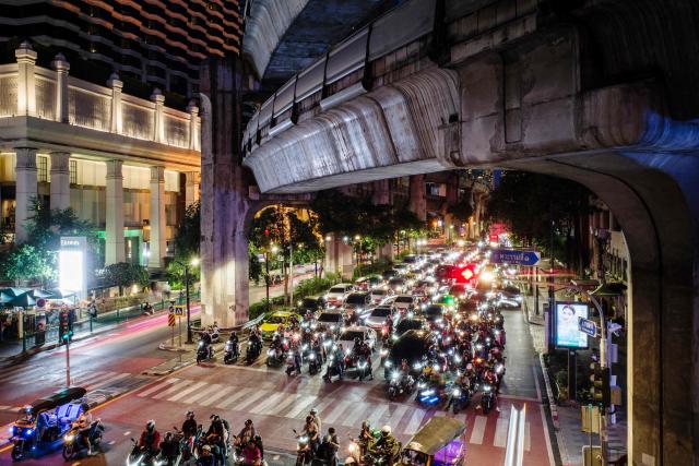 This long exposure photo shows motorists and drivers waiting at a red traffic light under the elevated concrete viaduct structure of the BTS Skytrain in Bangkok on June 9, 2026. (Photo by ANTHONY WALLACE / AFP)
