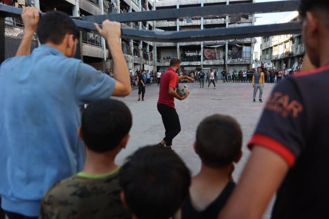 People watch Palestinians playing football inside a school sheltering displaced people at the Jabalia refugee camp in the northern Gaza Strip, on June 9, 2026. (Photo by Omar AL-QATTAA / AFP)