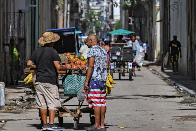 A man wearing shorts depicting the flag of the United States buys agricultural products from a vendor in a street in Havana on June 9, 2026. (Photo by YAMIL LAGE / AFP)