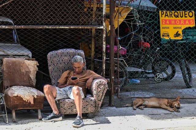 A man looks at his mobile phone outside a private parking in Havana on June 9, 2026. (Photo by YAMIL LAGE / AFP)