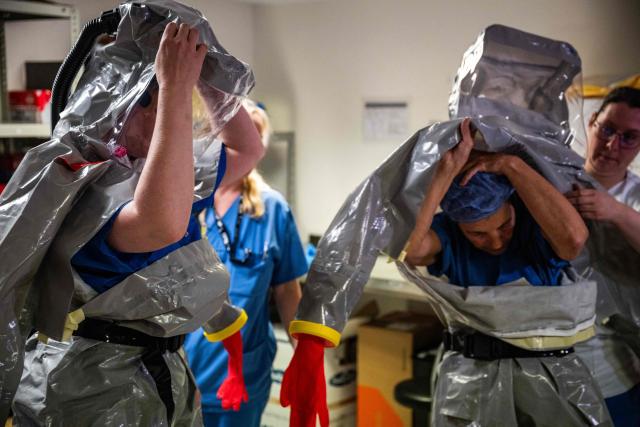 Nurses help their colleagues get into their PPE (Personal Protection Equipment) as they simulate the reception of a patient with a highly infectious disease such as Ebola, at the special isolation ward of the Department of Infectious Diseases at the Charite Virchow hospital in Berlin on June 9, 2026. The German hospital discharged a US man who caught Ebola in the Democratic Republic of Congo, after 17 days of antiviral treatment and medical care cured him of the often deadly infection. The Charite public hospital in Berlin said the man -- who had been working as a surgeon for a Christian missionary group in the DRC -- and his five family members who had all been in quarantine were in "good health" and permitted to leave. (Photo by John MACDOUGALL / AFP)