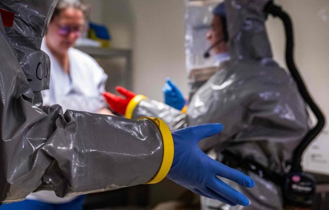 A nurse slips on protective gloves as she gets into her PPE (Personal Protection Equipment) as they simulate the reception of a patient with a highly infectious disease such as Ebola, at the special isolation ward of the Department of Infectious Diseases at the Charite Virchow hospital in Berlin on June 9, 2026. The German hospital discharged a US man who caught Ebola in the Democratic Republic of Congo, after 17 days of antiviral treatment and medical care cured him of the often deadly infection. The Charite public hospital in Berlin said the man -- who had been working as a surgeon for a Christian missionary group in the DRC -- and his five family members who had all been in quarantine were in "good health" and permitted to leave. (Photo by John MACDOUGALL / AFP)