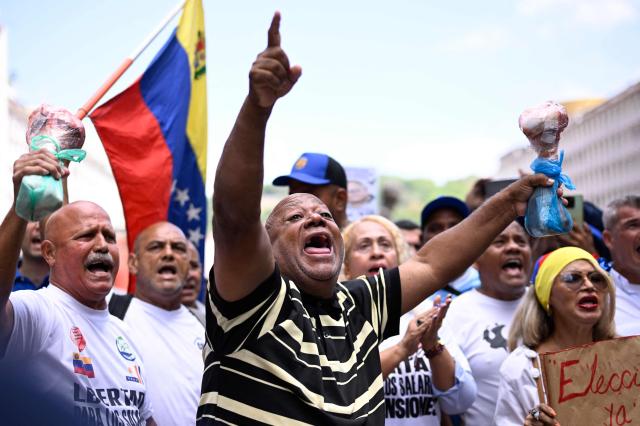 Union workers shout slogans as they hold up cow bones during a protest demanding better working conditions and presidential elections, outside the National Electoral Council (CNE) in Caracas on June 9, 2026. (Photo by Maxwell BRICENO / AFP)