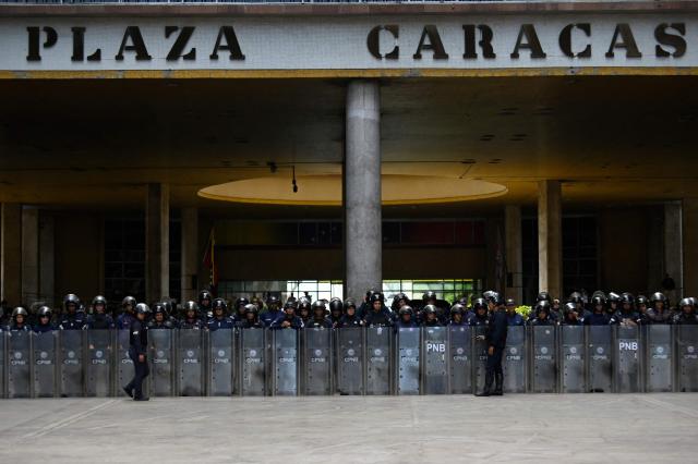 Members of the Bolivarian National Police Corps (CPNB) stand guard during a protest of unionists demanding better working conditions and presidential elections, outside the National Electoral Council (CNE) in Caracas on June 9, 2026. (Photo by Maxwell BRICENO / AFP)