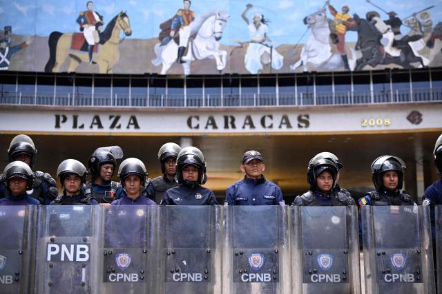Members of the Bolivarian National Police Corps (CPNB) stand guard during a protest of unionists demanding better working conditions and presidential elections, outside the National Electoral Council (CNE) in Caracas on June 9, 2026. (Photo by Maxwell BRICENO / AFP)