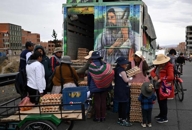 Locals buy eggs at an improvised market along a blocked highway in the Rio Seco area of El Alto, Bolivia, on June 9, 2026. The road, a key transport corridor linking La Paz with Copacabana and the border town of Desaguadero, has been transformed into a bustling marketplace where hundreds of vendors sell food and other goods as anti-government road blockades continue across the country amid growing political tensions and supply shortages. (Photo by Marvin RECINOS / AFP)