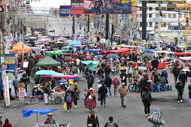 Locals walk at an improvised market along a blocked highway in the Rio Seco area of El Alto, Bolivia, on June 9, 2026. The road, a key transport corridor linking La Paz with Copacabana and the border town of Desaguadero, has been transformed into a bustling marketplace where hundreds of vendors sell food and other goods as anti-government road blockades continue across the country amid growing political tensions and supply shortages. (Photo by Marvin RECINOS / AFP)