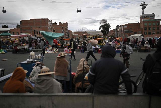 People walk at an improvised market along a blocked highway in the Rio Seco area of El Alto, Bolivia, on June 9, 2026. The road, a key transport corridor linking La Paz with Copacabana and the border town of Desaguadero, has been transformed into a bustling marketplace where hundreds of vendors sell food and other goods as anti-government road blockades continue across the country amid growing political tensions and supply shortages. (Photo by Marvin RECINOS / AFP)