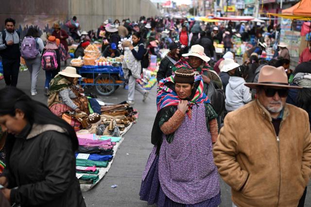People walk at an improvised market along a blocked highway in the Rio Seco area of El Alto, Bolivia, on June 9, 2026. The road, a key transport corridor linking La Paz with Copacabana and the border town of Desaguadero, has been transformed into a bustling marketplace where hundreds of vendors sell food and other goods as anti-government road blockades continue across the country amid growing political tensions and supply shortages. (Photo by Marvin RECINOS / AFP)