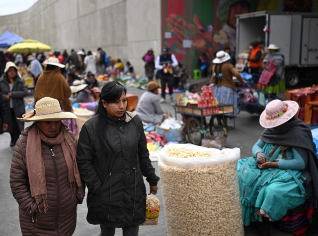 People walk at an improvised market along a blocked highway in the Rio Seco area of El Alto, Bolivia, on June 9, 2026. The road, a key transport corridor linking La Paz with Copacabana and the border town of Desaguadero, has been transformed into a bustling marketplace where hundreds of vendors sell food and other goods as anti-government road blockades continue across the country amid growing political tensions and supply shortages. (Photo by Marvin RECINOS / AFP)