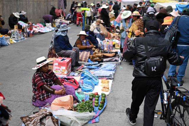 People walk at an improvised market along a blocked highway in the Rio Seco area of El Alto, Bolivia, on June 9, 2026. The road, a key transport corridor linking La Paz with Copacabana and the border town of Desaguadero, has been transformed into a bustling marketplace where hundreds of vendors sell food and other goods as anti-government road blockades continue across the country amid growing political tensions and supply shortages. (Photo by Marvin RECINOS / AFP)