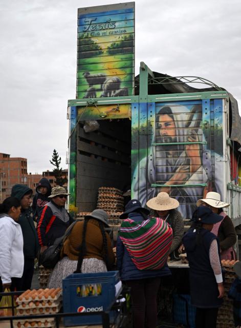 People buy eggs at an improvised market along a blocked highway in the Rio Seco area of El Alto, Bolivia, on June 9, 2026. The road, a key transport corridor linking La Paz with Copacabana and the border town of Desaguadero, has been transformed into a bustling marketplace where hundreds of vendors sell food and other goods as anti-government road blockades continue across the country amid growing political tensions and supply shortages. (Photo by Marvin RECINOS / AFP)