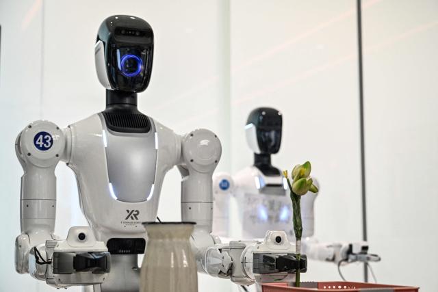 Humanoid robots are trained to do household tasks at the X Square Robot facilities in Shenzhen, southern China's Guangdong province on May 22, 2026. China's robots have wowed audiences with fluid dancing and set-piece martial arts displays onstage, but their application and performance in real-life settings remains limited. For companies like X Square, the logic of launching an imperfect service lies in data collection for so-called embodied artificial intelligence. (Photo by Hector RETAMAL / AFP) / To go with AFP story China-tech-labour-lifestyle-AI, FOCUS by Emily WANG
