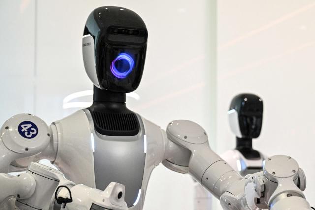 Humanoid robots are trained to do household tasks at the X Square Robot facilities in Shenzhen, southern China's Guangdong province on May 22, 2026. China's robots have wowed audiences with fluid dancing and set-piece martial arts displays onstage, but their application and performance in real-life settings remains limited. For companies like X Square, the logic of launching an imperfect service lies in data collection for so-called embodied artificial intelligence. (Photo by Hector RETAMAL / AFP) / To go with AFP story China-tech-labour-lifestyle-AI, FOCUS by Emily WANG